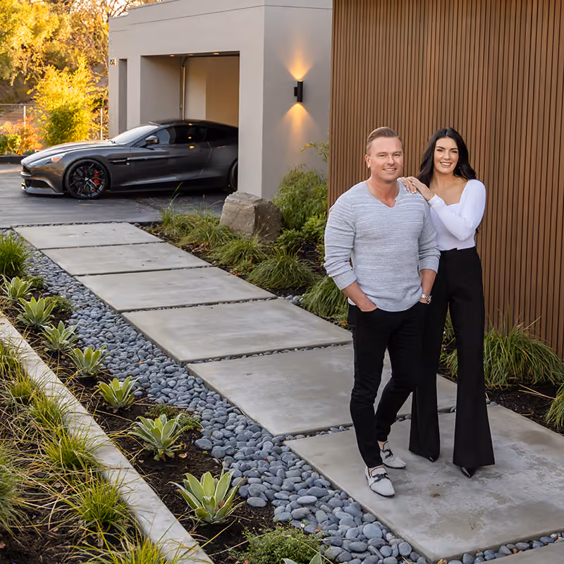 Anton Danilovich and rivereastbay Coyle in front of a modern Bay Area home